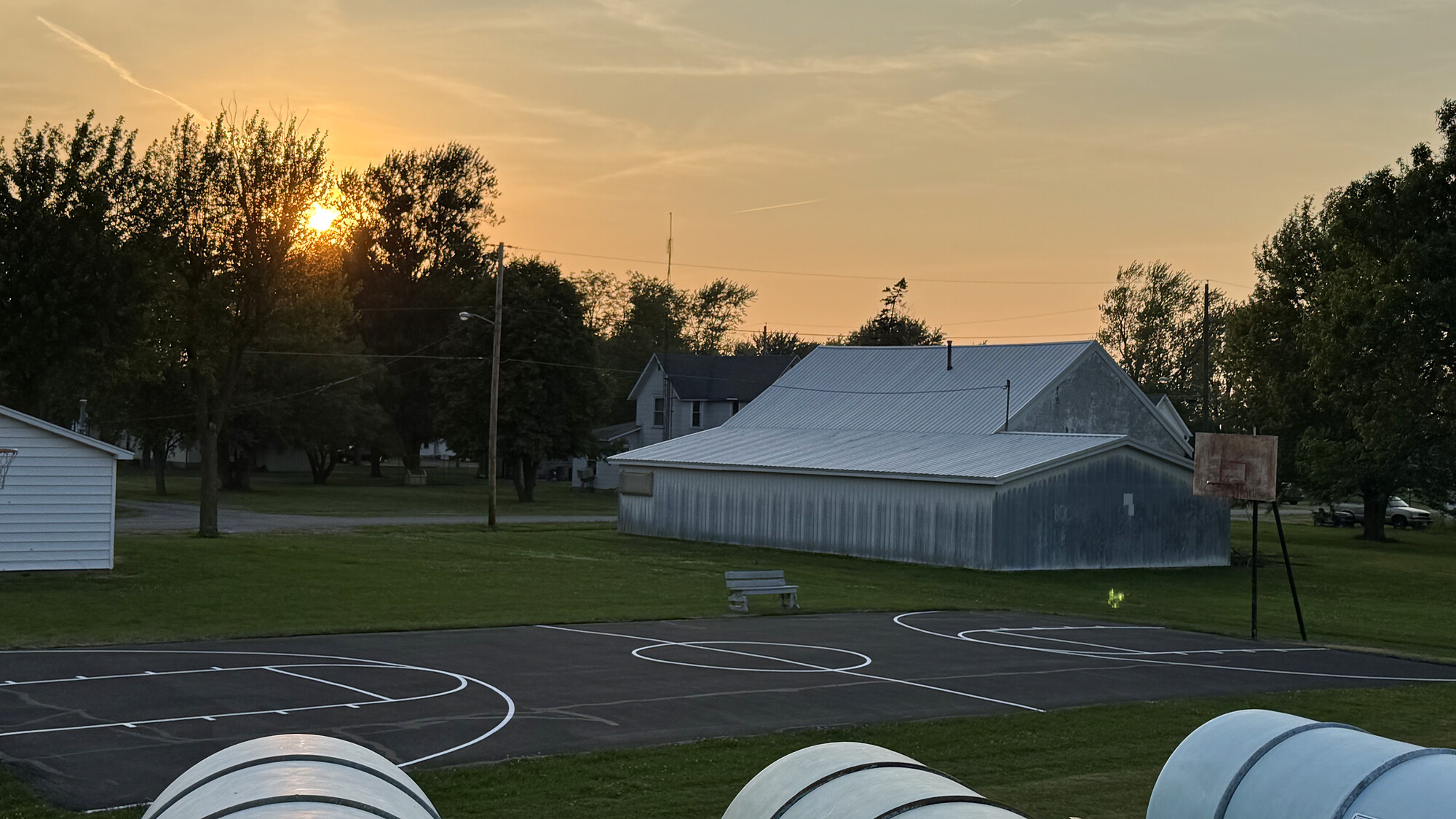 Freshly painted outdoor basketball court at sunset with crisp white markings and basketball hoops