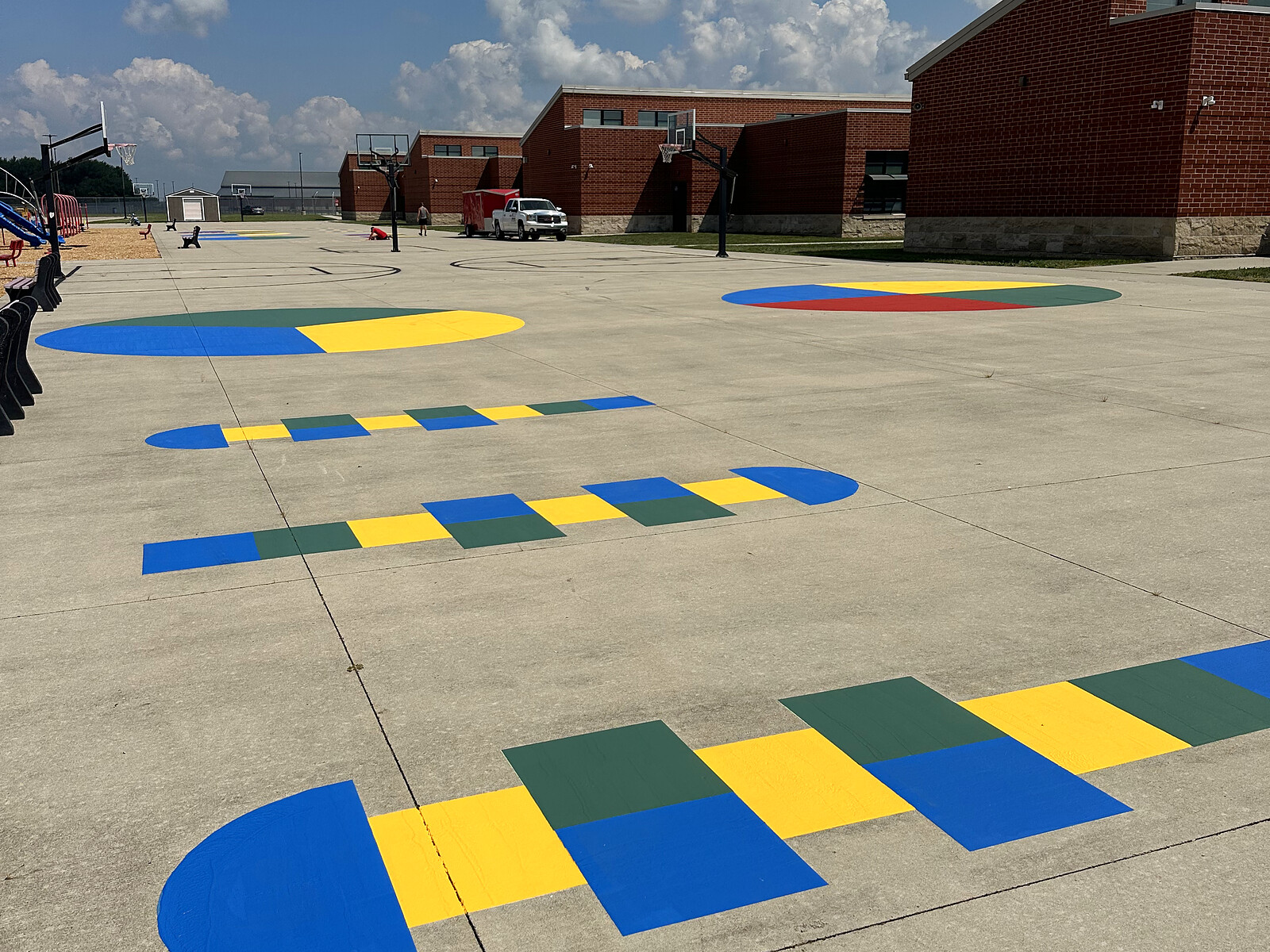 Colorful blue, yellow, and green painted playground game patterns at a school