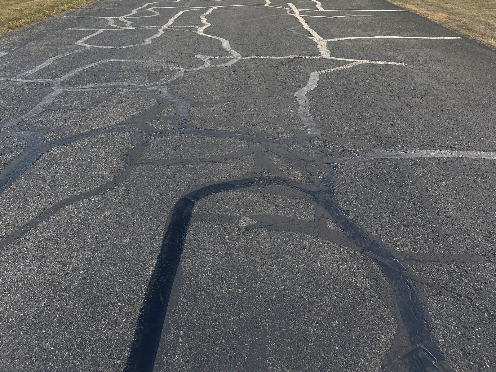 Close-up of fresh hot rubber crack filling on asphalt pavement