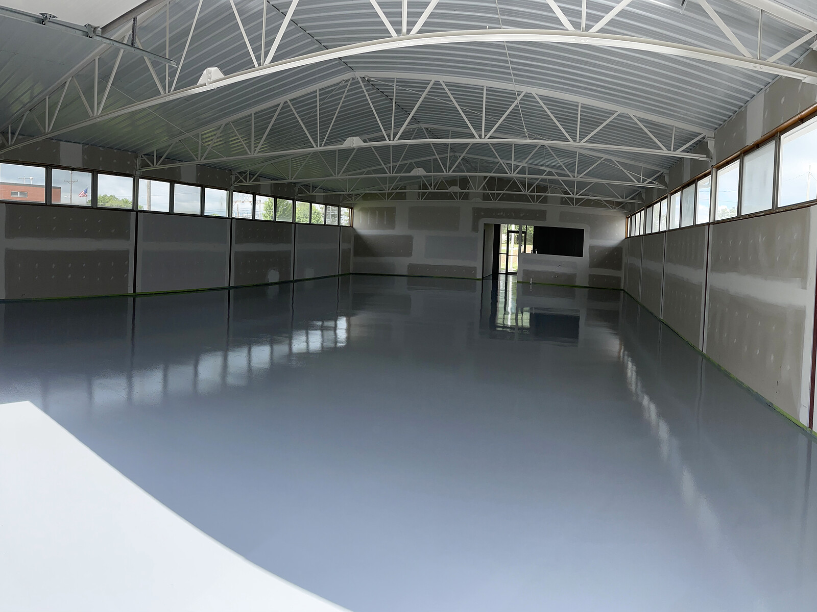 Two-tone gray epoxy floor in a commercial building with curved truss roof