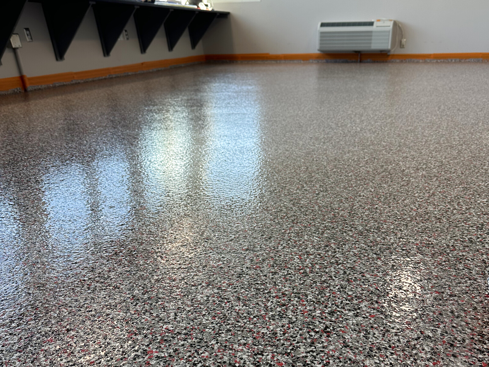 Gray, black, white, and red flake epoxy floor in an athletic facility locker room