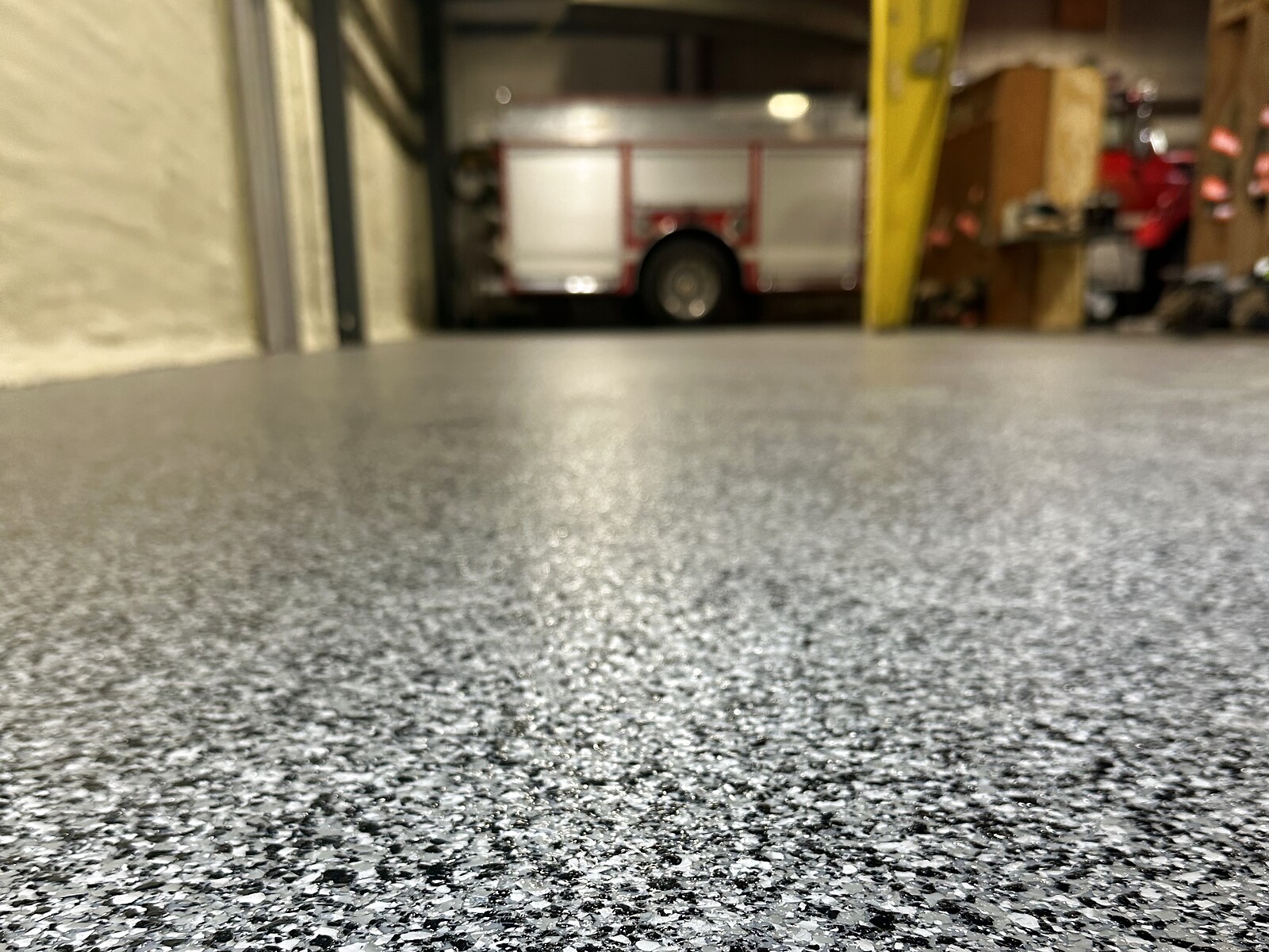 Gray and black flake epoxy floor in a fire station bay with a fire engine in the background