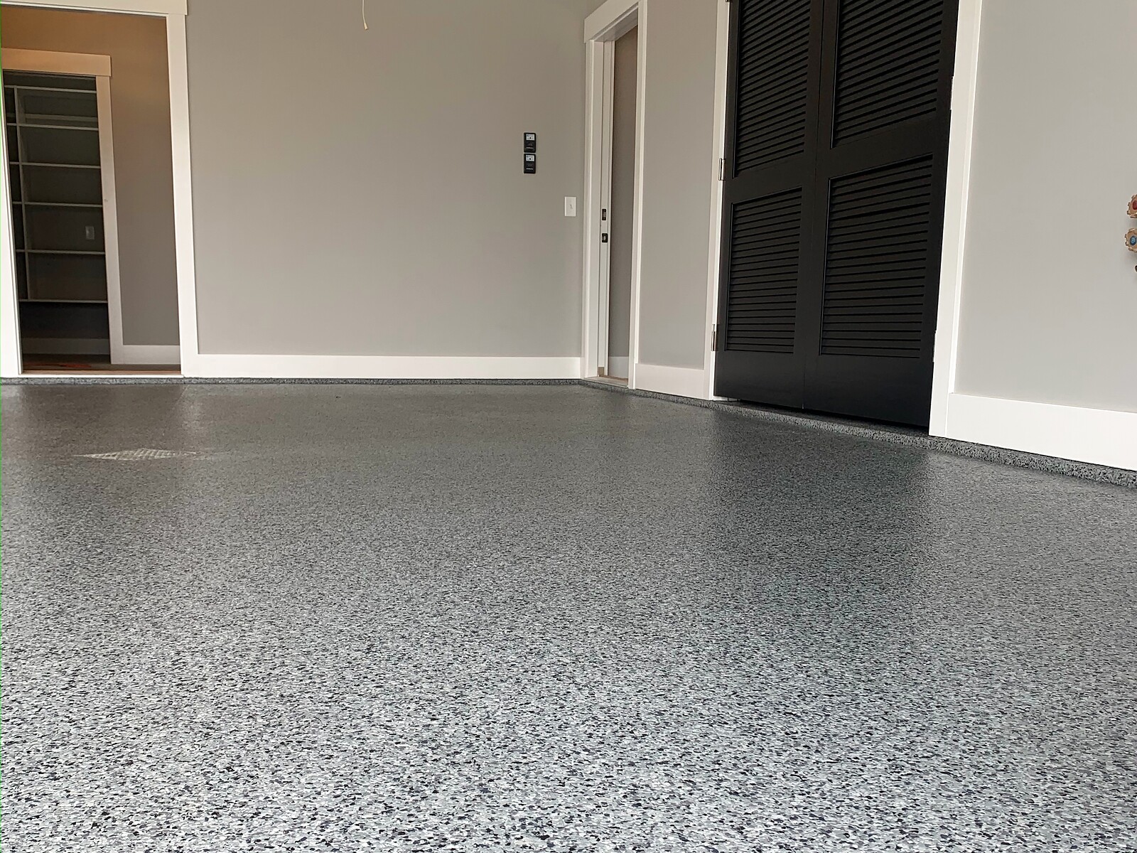 Gray flake epoxy floor in a finished residential interior with louvered closet doors and clean trim